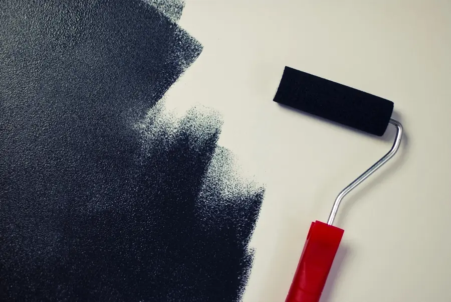 Roller painting a wall dark grey