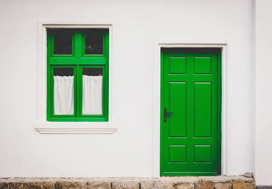 White rendered wall with green door and window